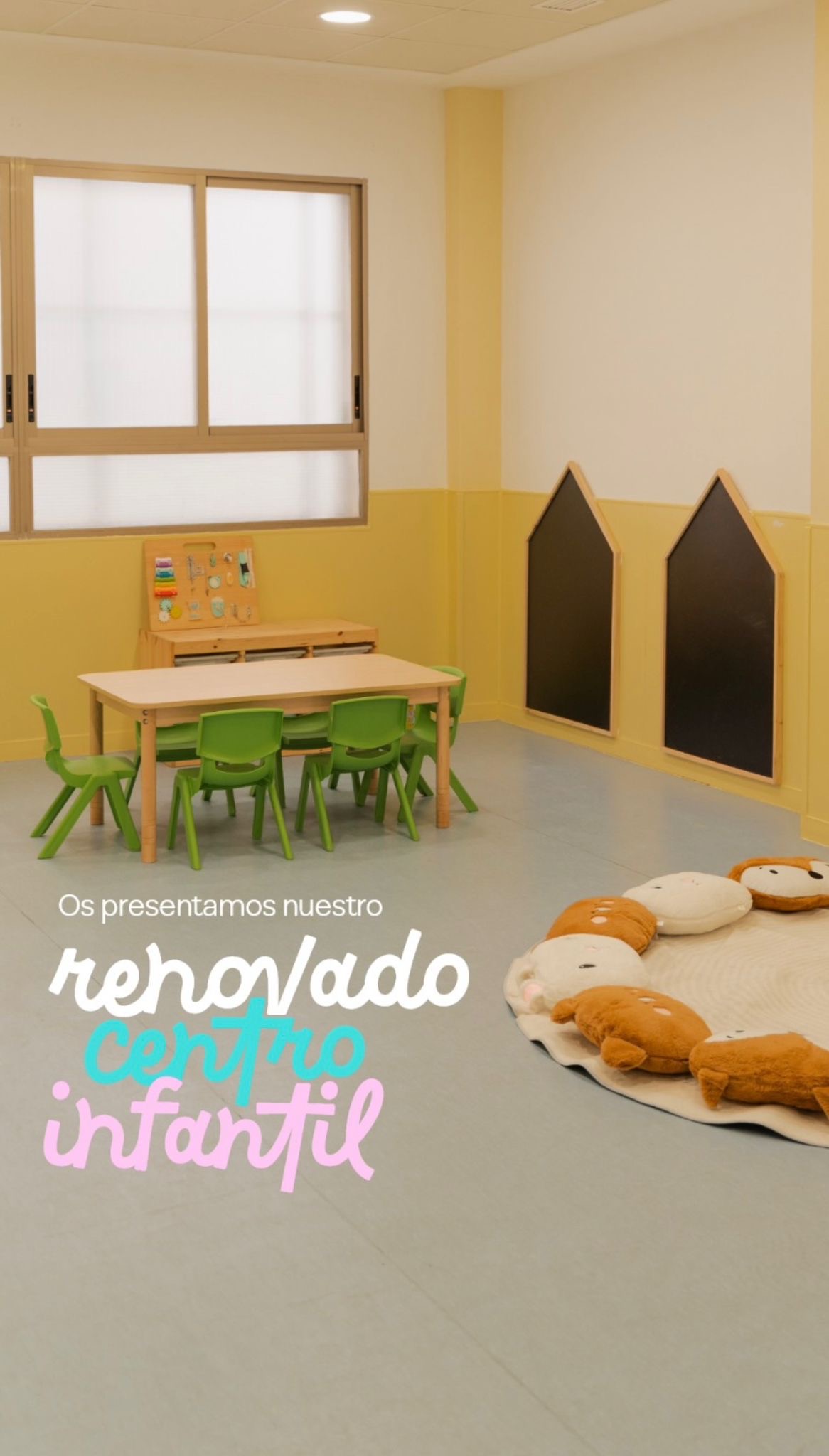 Aula renovada con mesa y sillas verdes a la altura de los niños, dos pizarras con forma de casita y una alfombra rodeada de cojines de animales. Texto en la imagen: os presentamos nuestro renovado centro infantil.