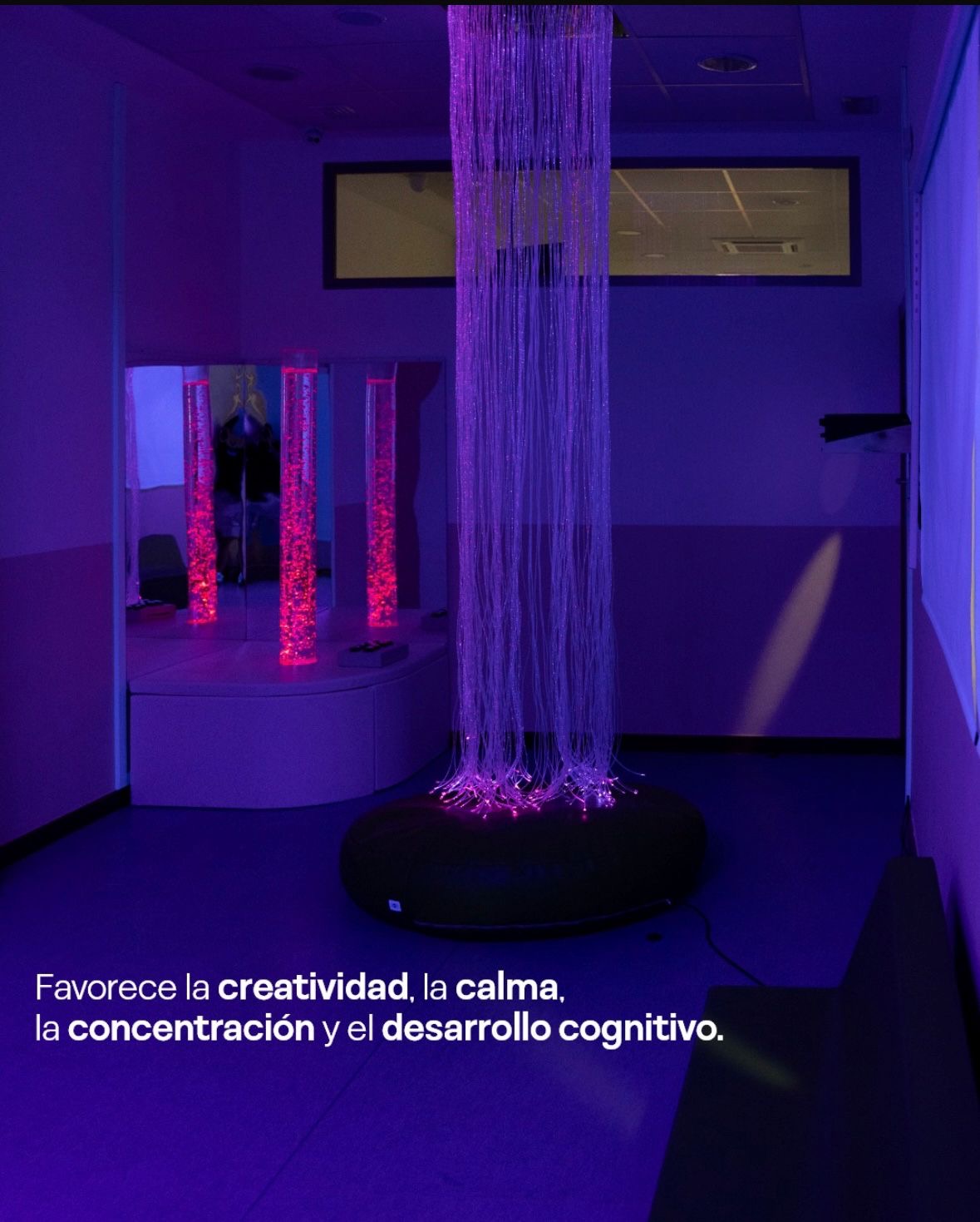 Vista general de la sala sensorial con la cortina de fibra óptica sobre un puf y las columnas de burbujas reflejadas en un espejo. Texto en la imagen: favorece la creatividad, la calma, la concentración y el desarrollo cognitivo.