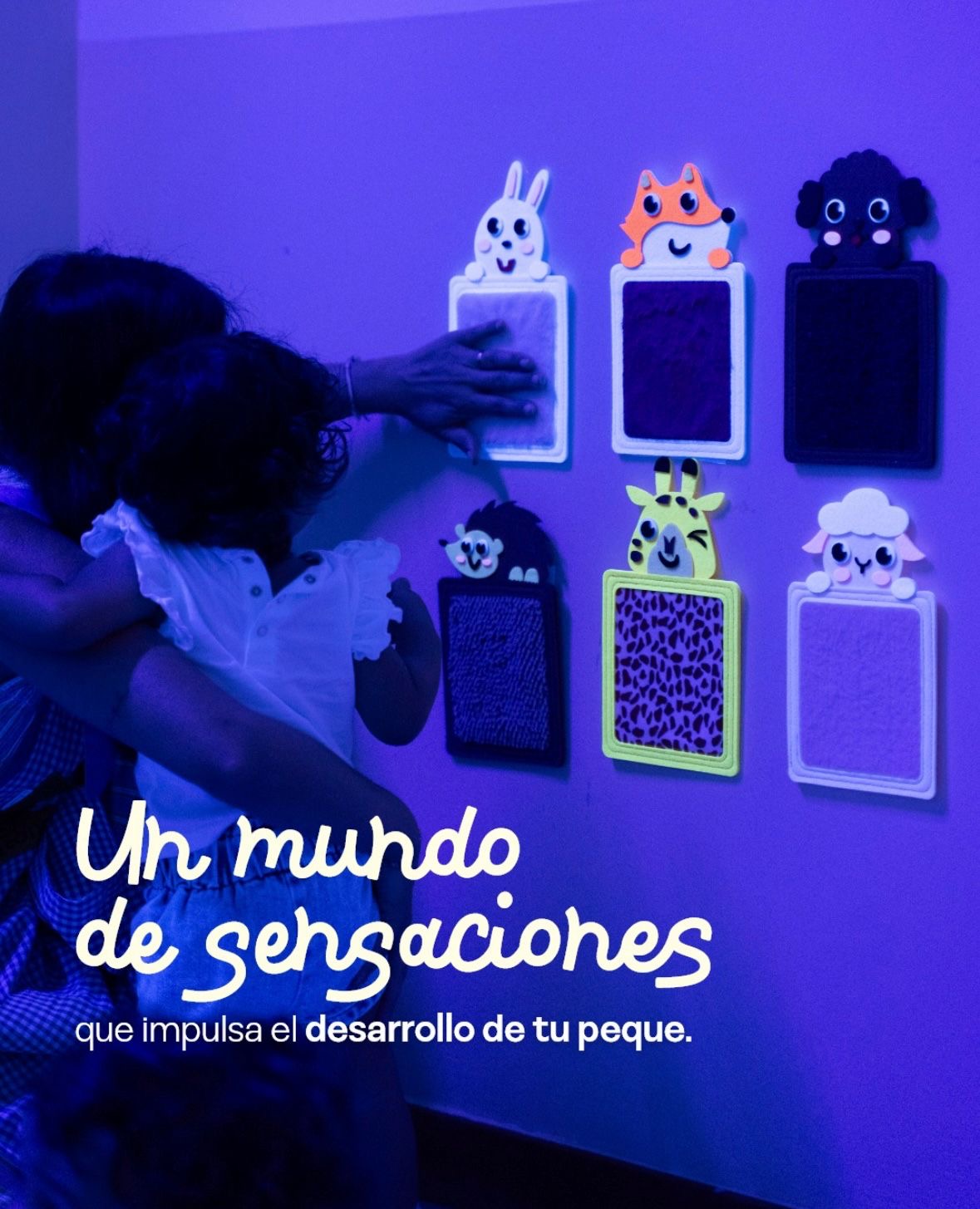 Panel de pared con figuras de animales de distintas texturas que una niña explora con las manos acompañada de su tutora. Texto en la imagen: un mundo de sensaciones que impulsa el desarrollo de tu peque.